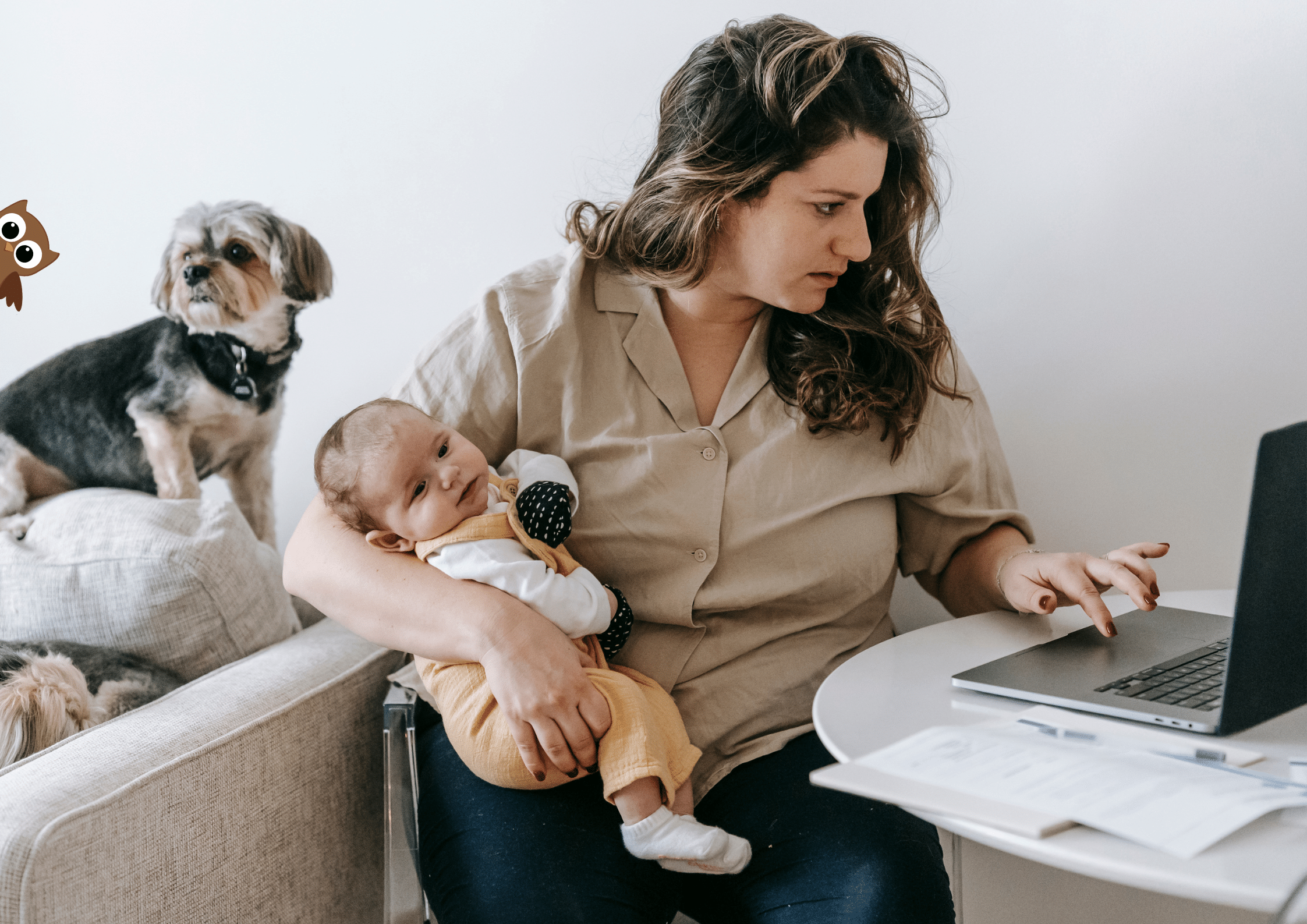 Working Parent holding a baby while on her laptop